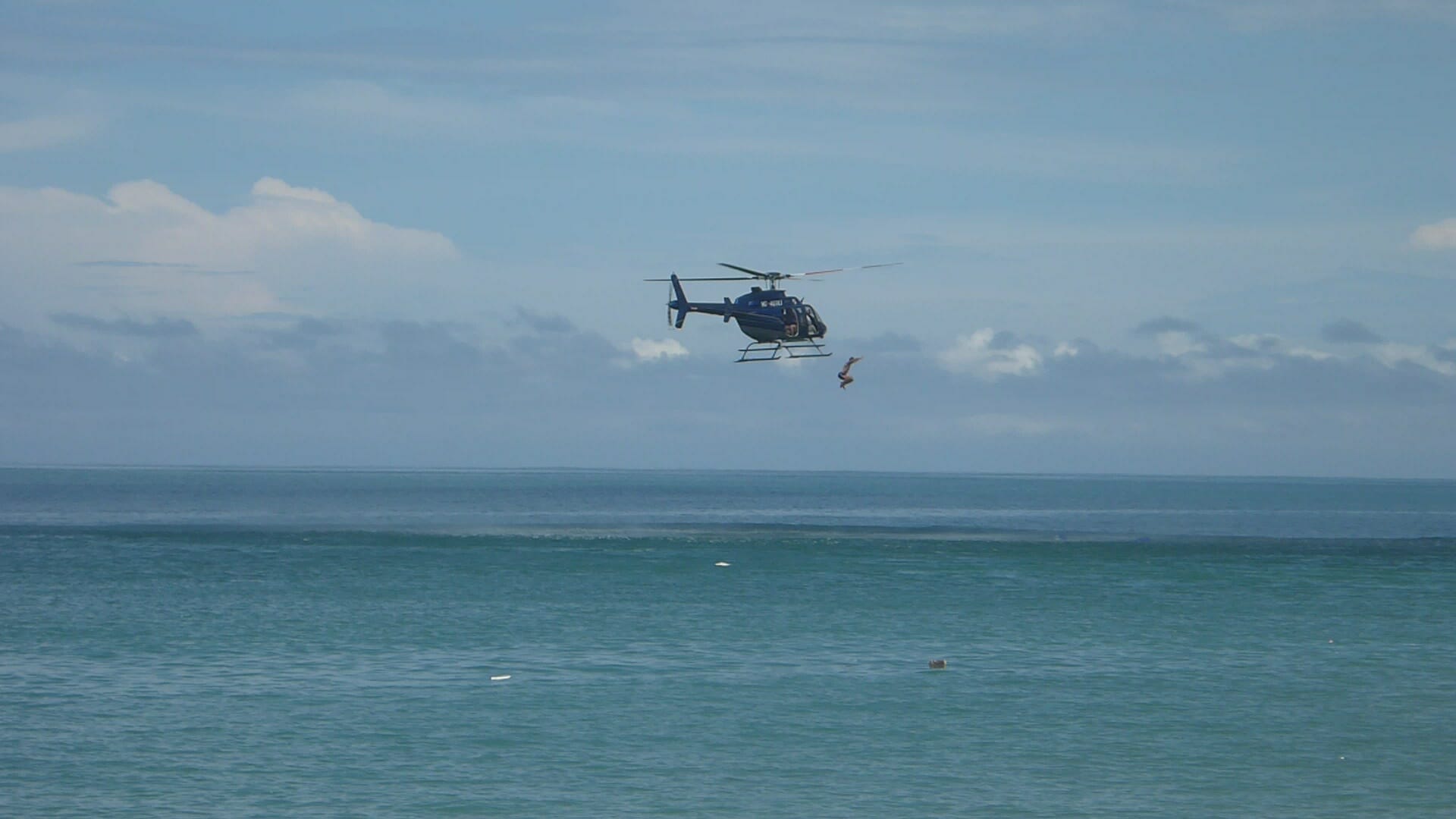 A private helicopter soaring over the ocean.