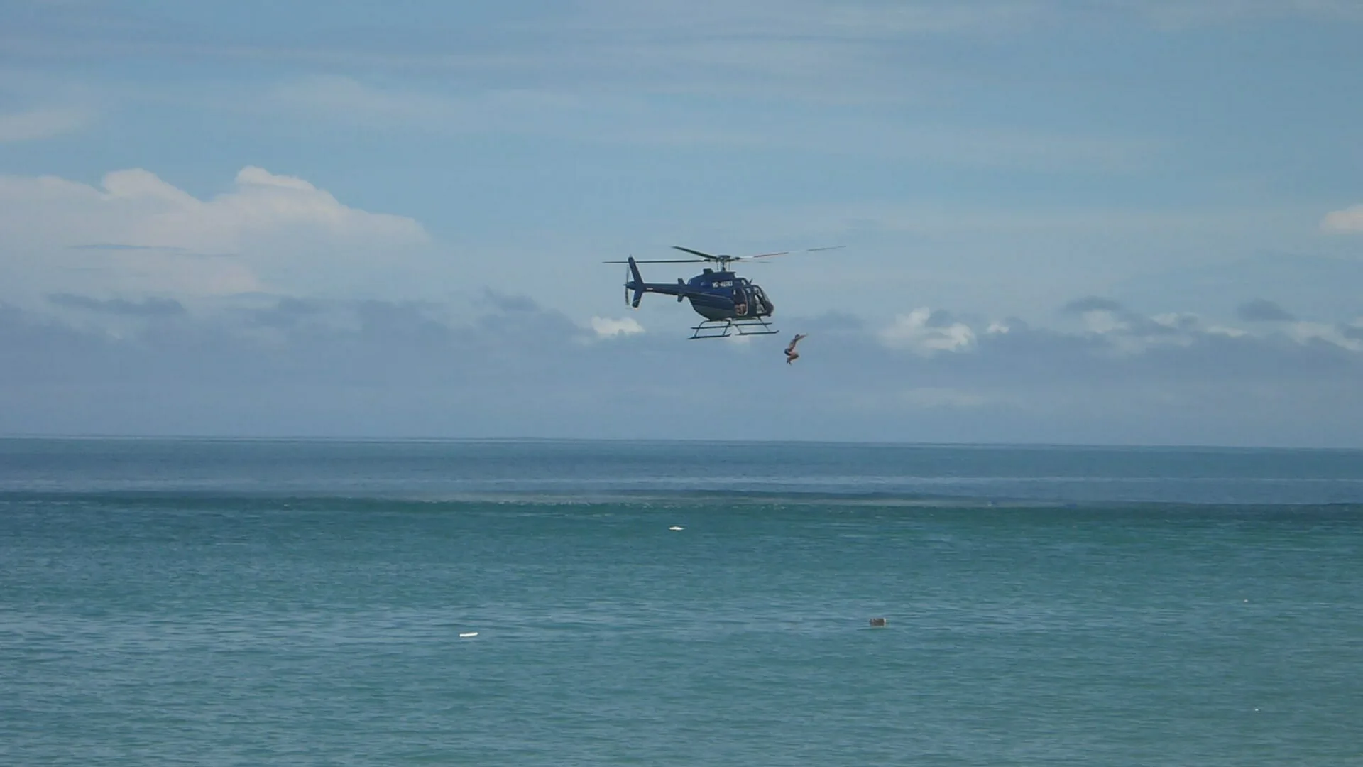 A private helicopter soaring over the ocean.