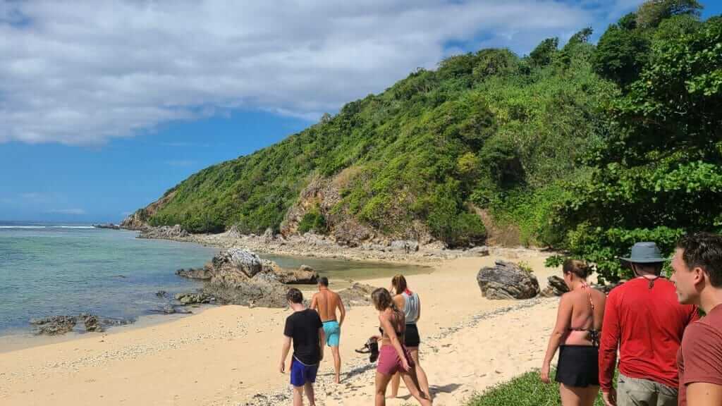 A group of people standing on a sandy beach.