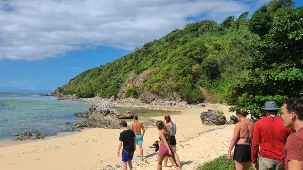A group of people standing on a sandy beach.