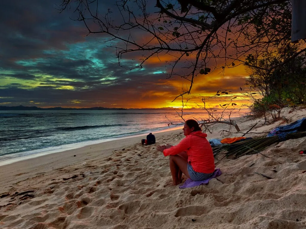 A woman watching the sunset from a desert island