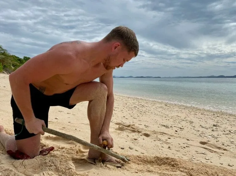 A man using a shovel on a desert island.