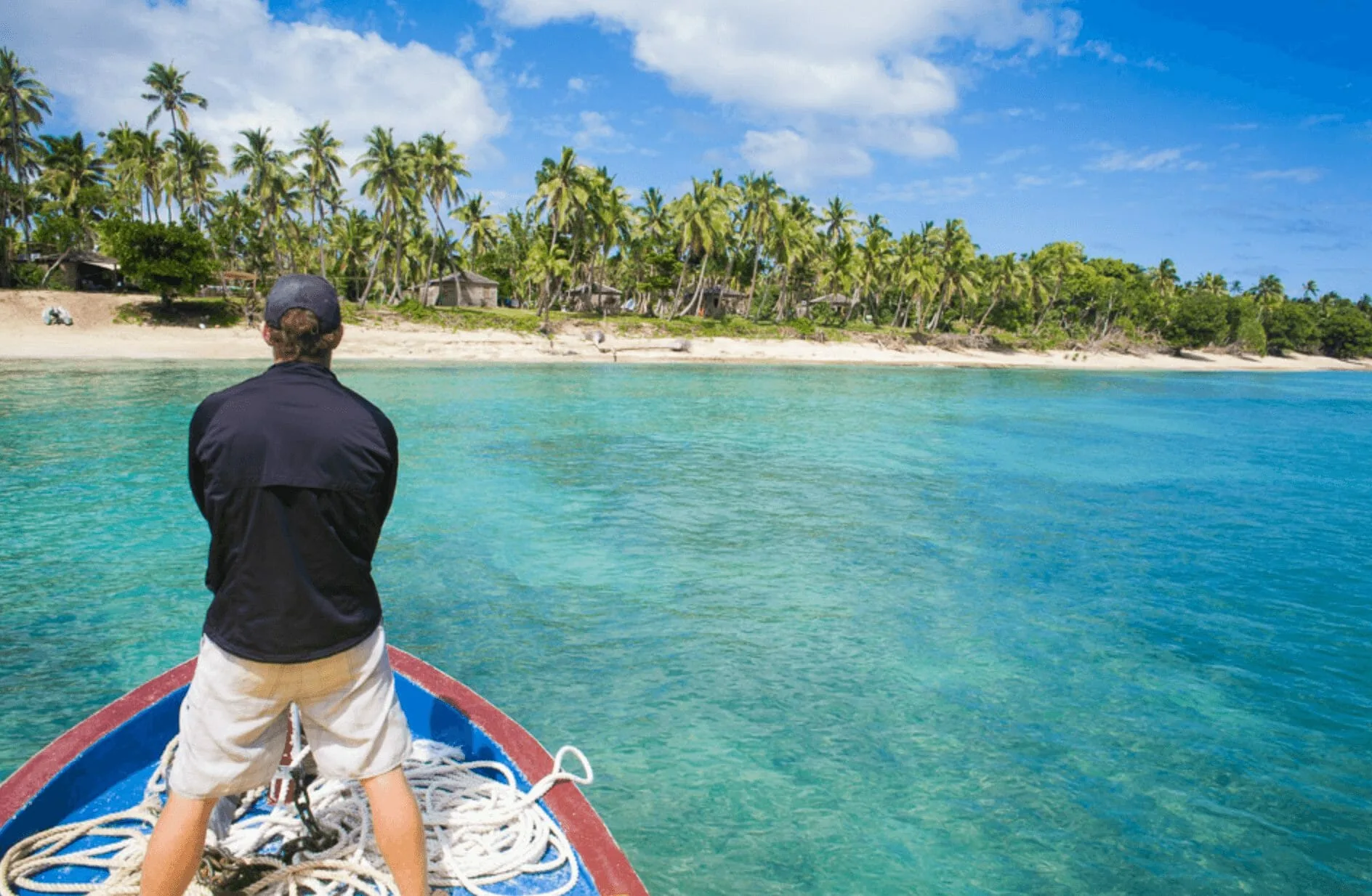 A man is standing on the back of a boat in Tonga.