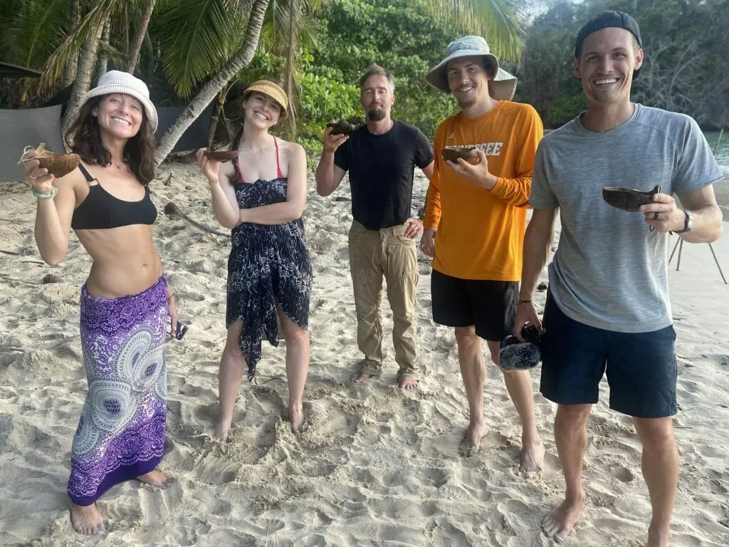 People drinking out of coconut bowls on the beach