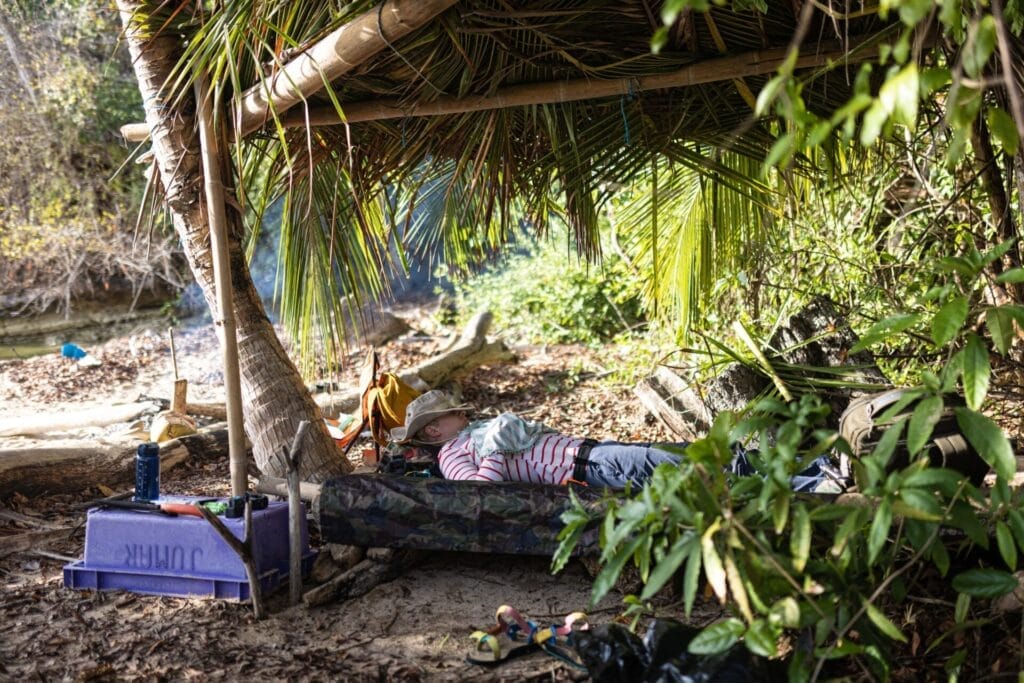 woman sleeping in survival shelter on beach