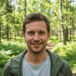 Sweden Alone bushcraft survival experience 26 A smiling man in a forest setting, wearing casual outdoor clothing, surrounded by tall trees and lush greenery, emphasizing wilderness exploration and survival skills.