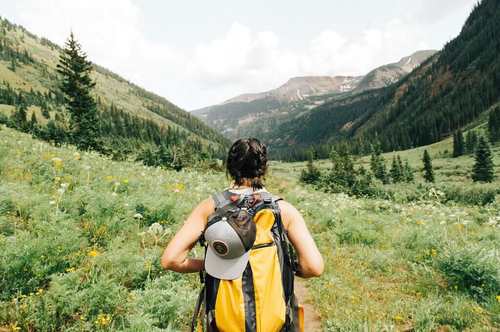 Adventure Travel: An Exhilarating Way to Explore the World 3 person carrying yellow and black backpack walking between green plants