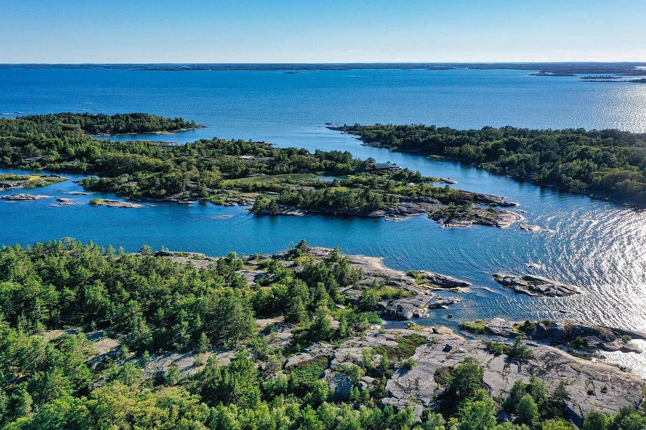 Sweden archipelago aerial view. Islands with trees and rocky shores in blue water.