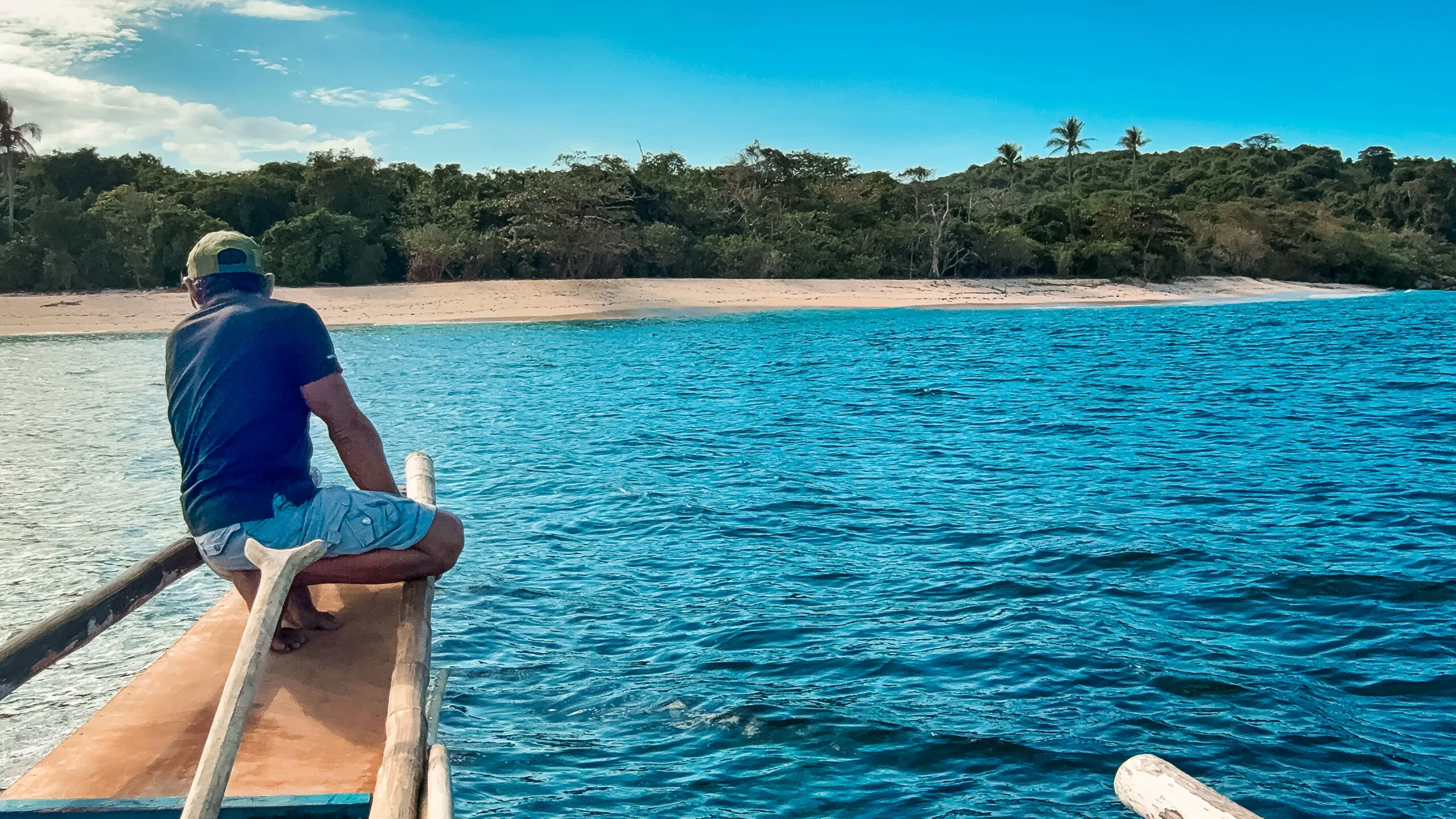 Man on boat looking at tropical island. Possible survivor strategies location.