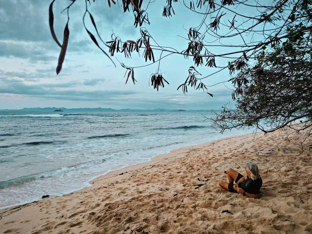 Woman relaxing on a sandy beach, possibly reflecting on survivor strategies.