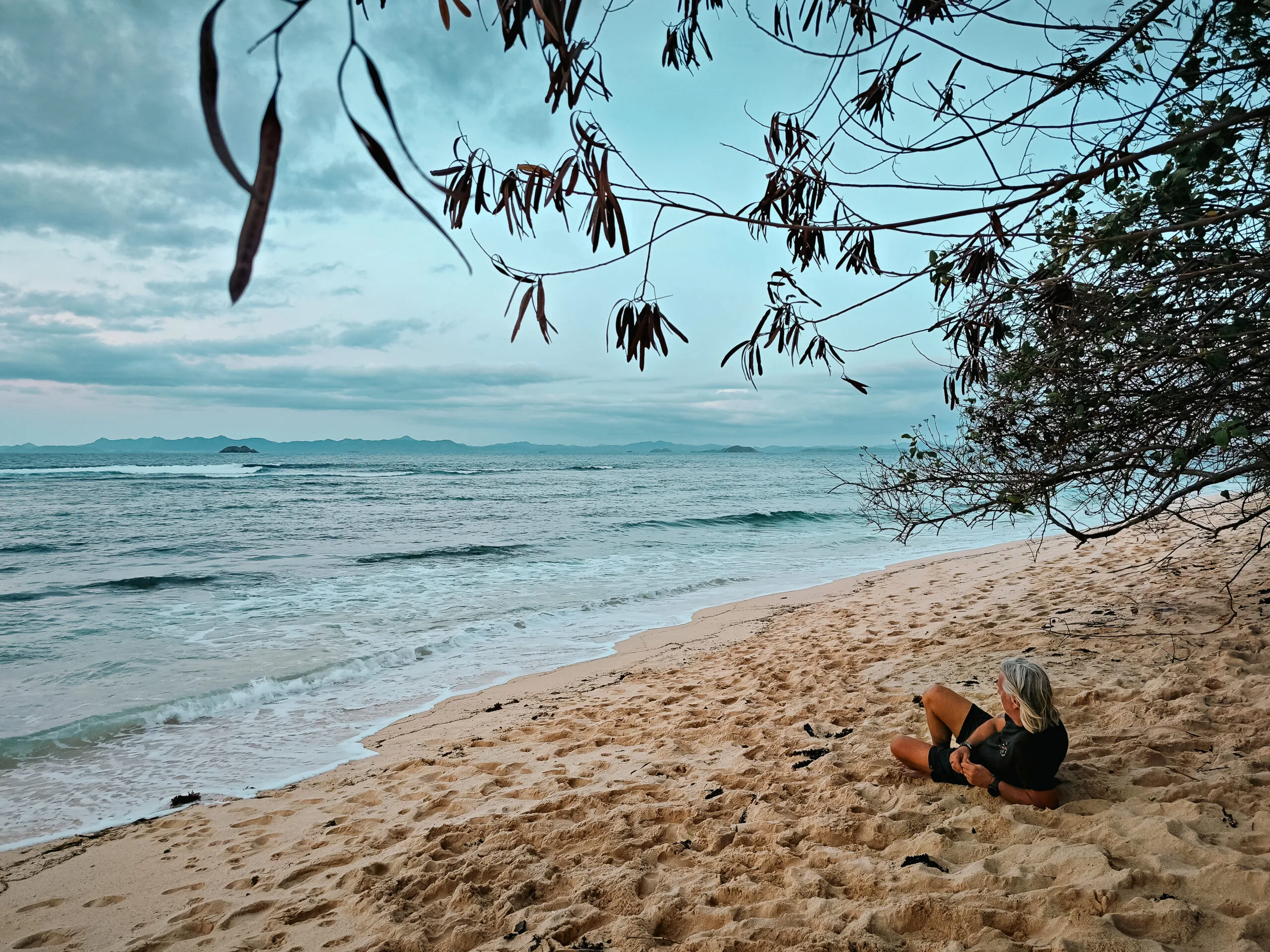 Woman relaxing on a sandy beach, possibly reflecting on survivor strategies.