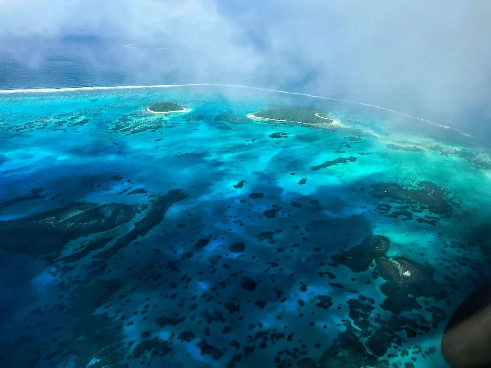 Aerial view of turquoise waters and small islands in Tonga, showcasing the beauty of Tonga in May.