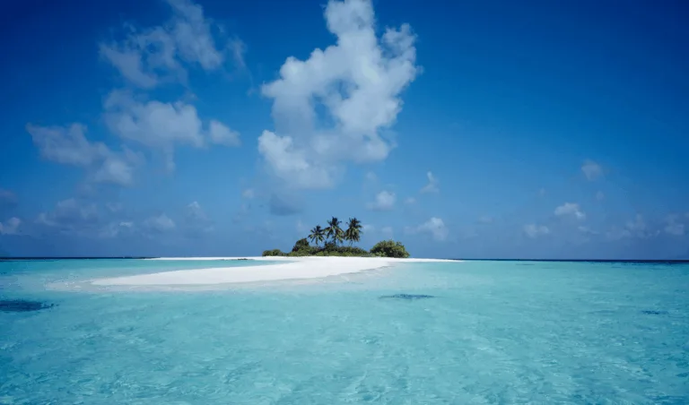 Secluded Maldives island with white sand beach, palm trees, and clear turquoise water.