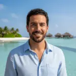 Desert Island Survival Adventure in the Maldives 33 Man smiling on tropical beach with overwater bungalows, paradise island, and clear blue water.