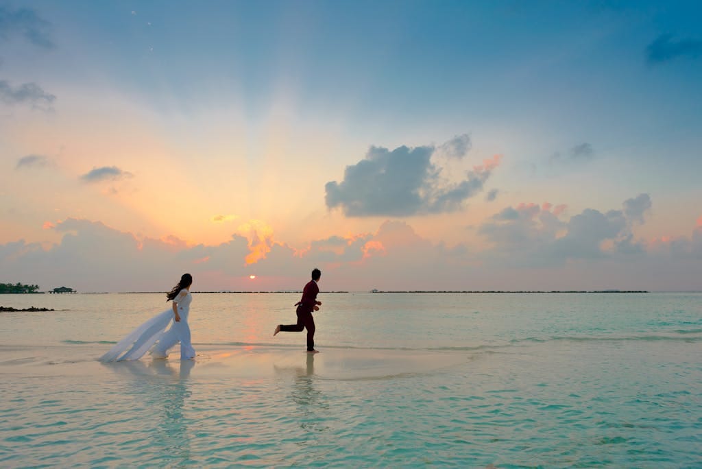 The Maldives Beyond Honeymoons. Adventure Meets Paradise 1 A couple enjoys a romantic moment running on a tropical beach during sunrise, capturing love and joy.