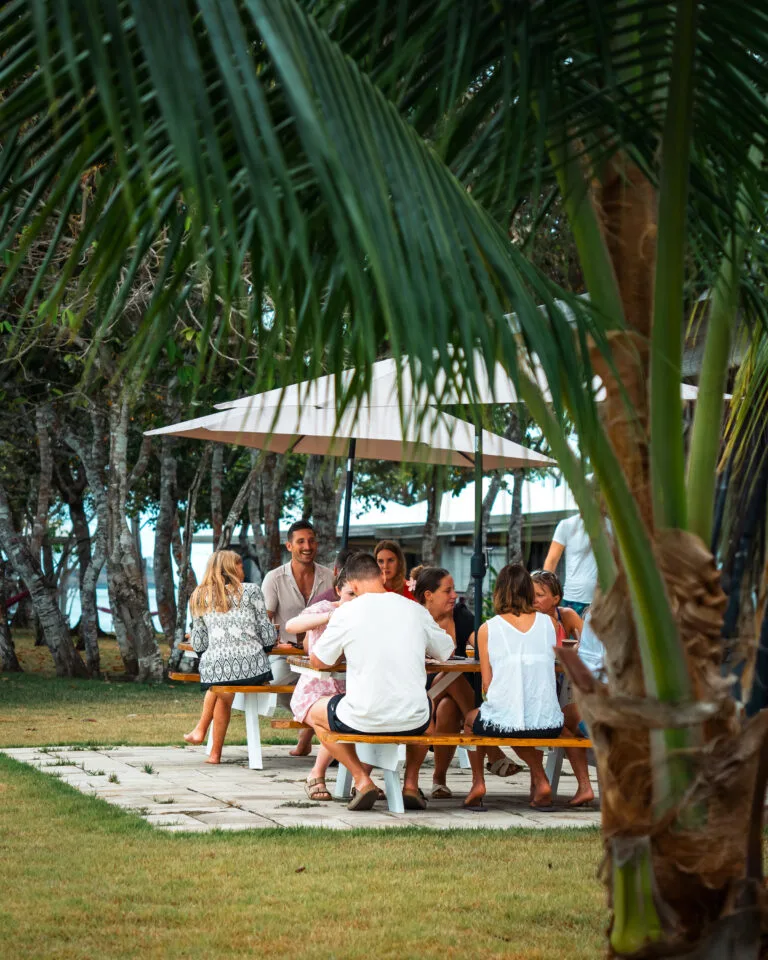 Group enjoying an outdoor picnic at Private Adventures, under a sun umbrella.