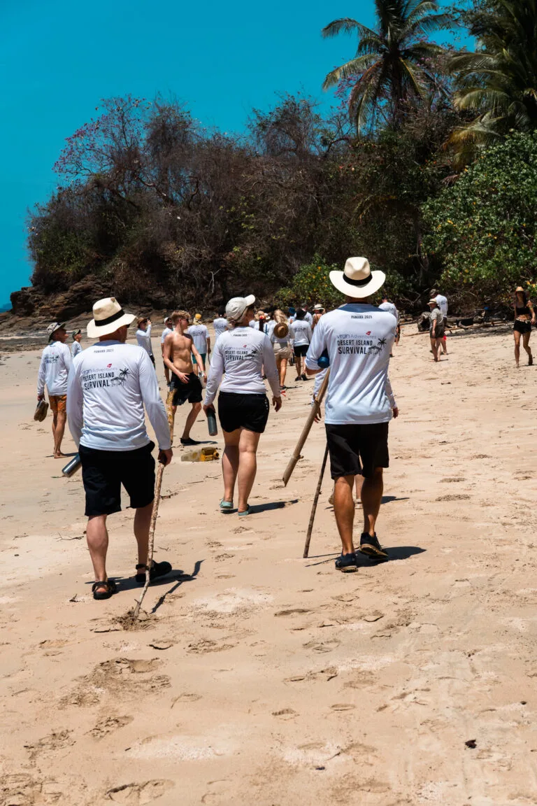 Group walking on beach, "Desert Island Survival, Panama 2025" t-shirts.
