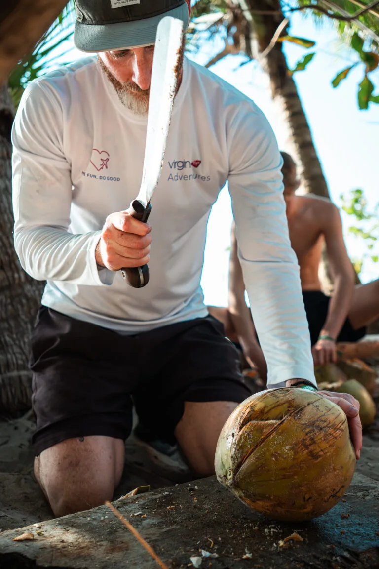 Man opening a coconut with a machete during a Virgin Adventures experience.