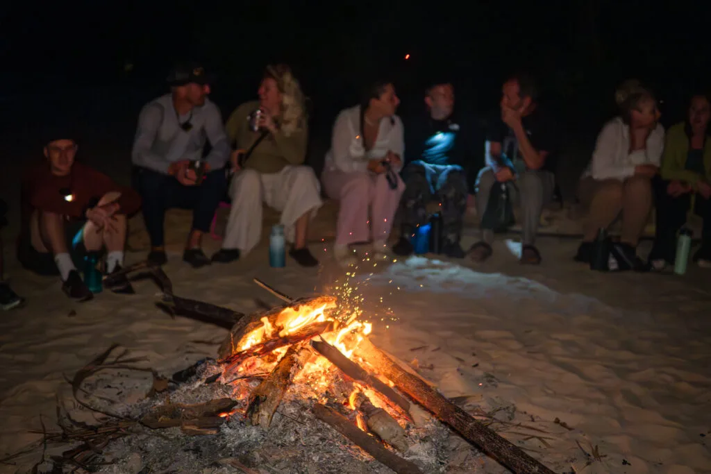 People gathered around a campfire on a beach, enjoying a day without technology.