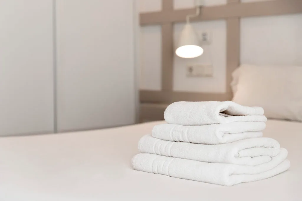 Stack of fresh white towels on a luxurious hotel bed.