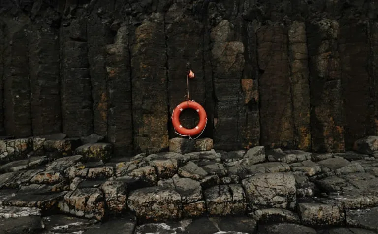 Orange life preserver hanging against basalt columns, emphasizing safety on our adventures.