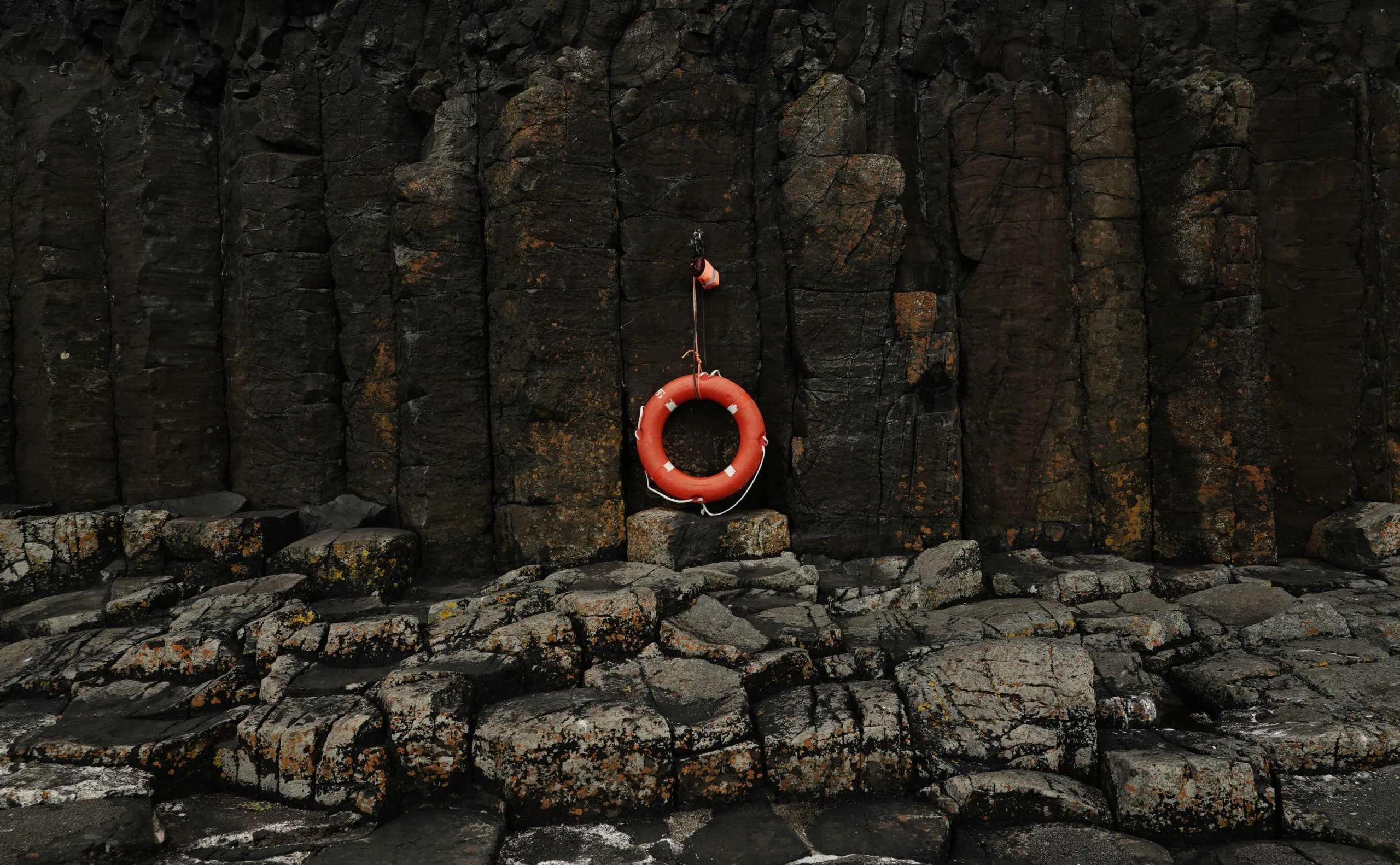 Orange life preserver hanging against basalt columns, emphasizing safety on our adventures.