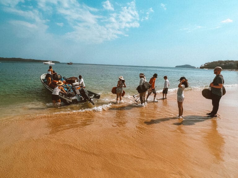 Private Group Adventures 8 Packing luggage onto a boat on a tropical beach for island survival or travel.