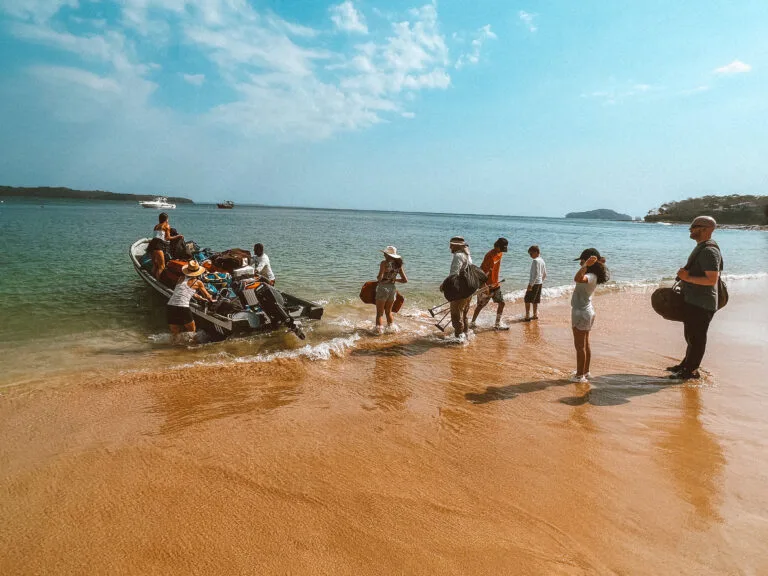 Packing luggage onto a boat on a tropical beach for island survival or travel.