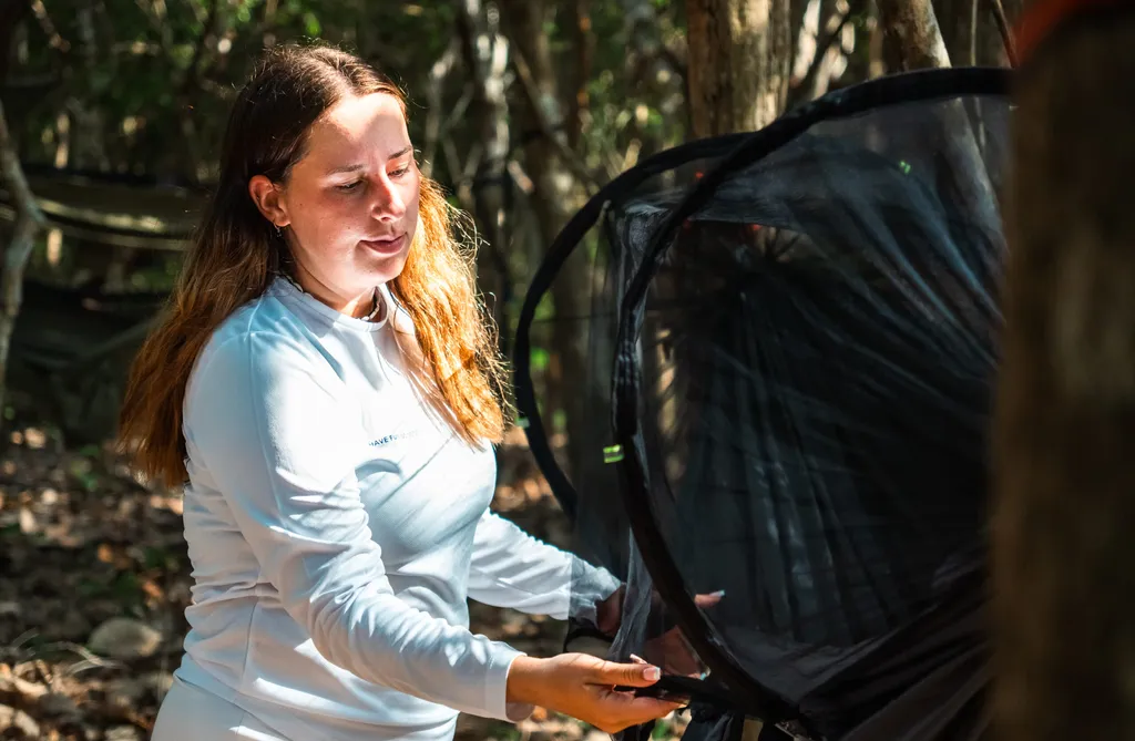 Survival skills on a desert island, woman using mosquito net in jungle.