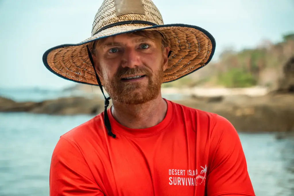 Meet the Instructors: Firemakers, Fear-Tamers, Foundational Humans 2 Man wearing a wide-brimmed straw hat on a deserted island beach for survival tips.