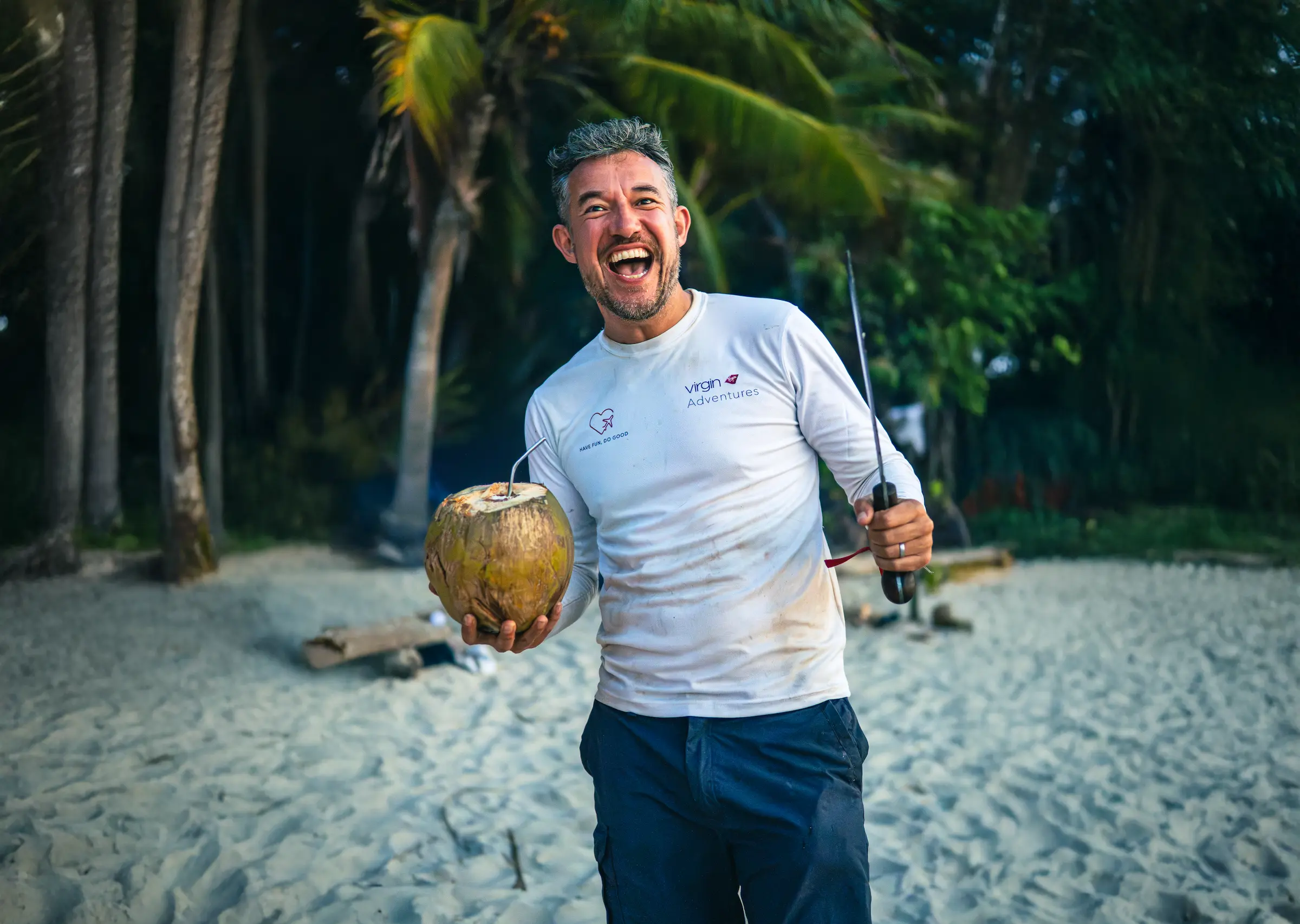 Coconut drink on a deserted island with a man smiling, tropical survival, adventure, beach life, escape from civilization.