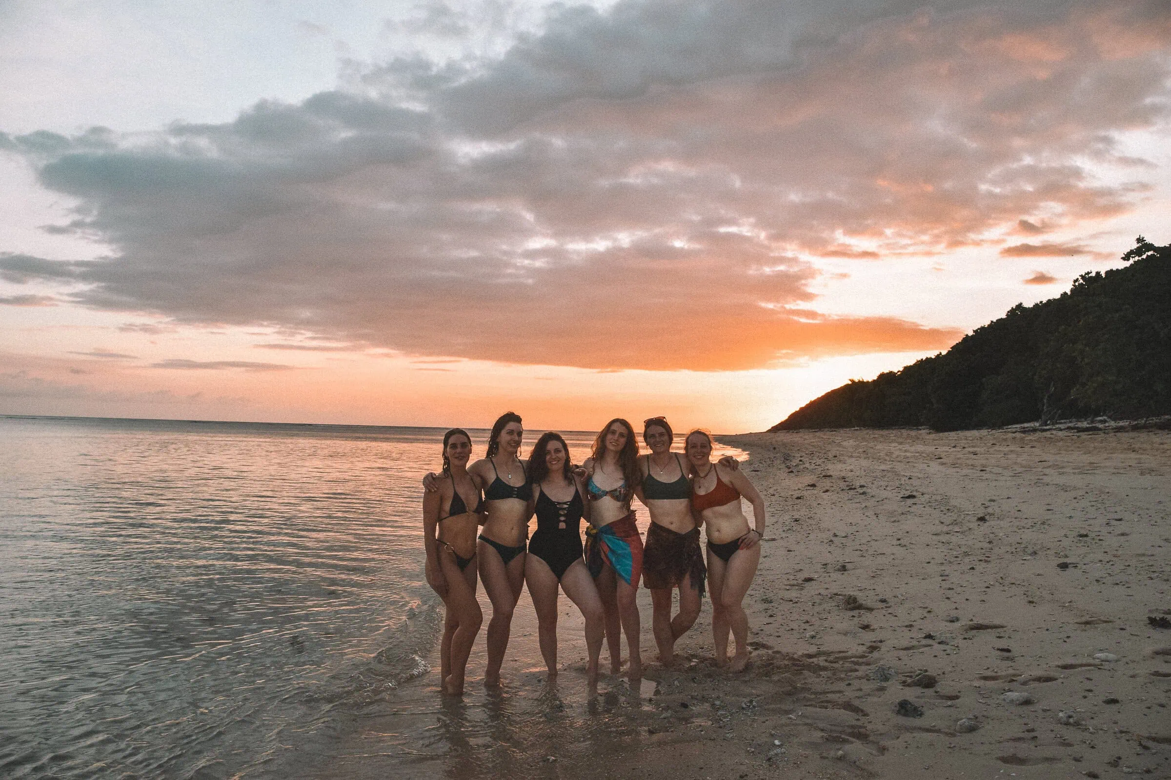 Beach survival skills demonstration on a tropical island during sunset.