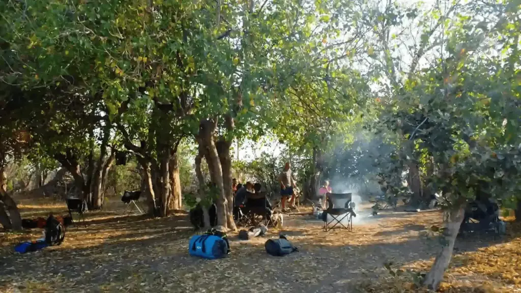 Botswana Kayak Bushcraft Safari in the Okavango Delta 1 Finding shelter and relaxing under the shade of trees on a deserted island, with camping gear and a campfire, perfect for survival and outdoor adventure.
