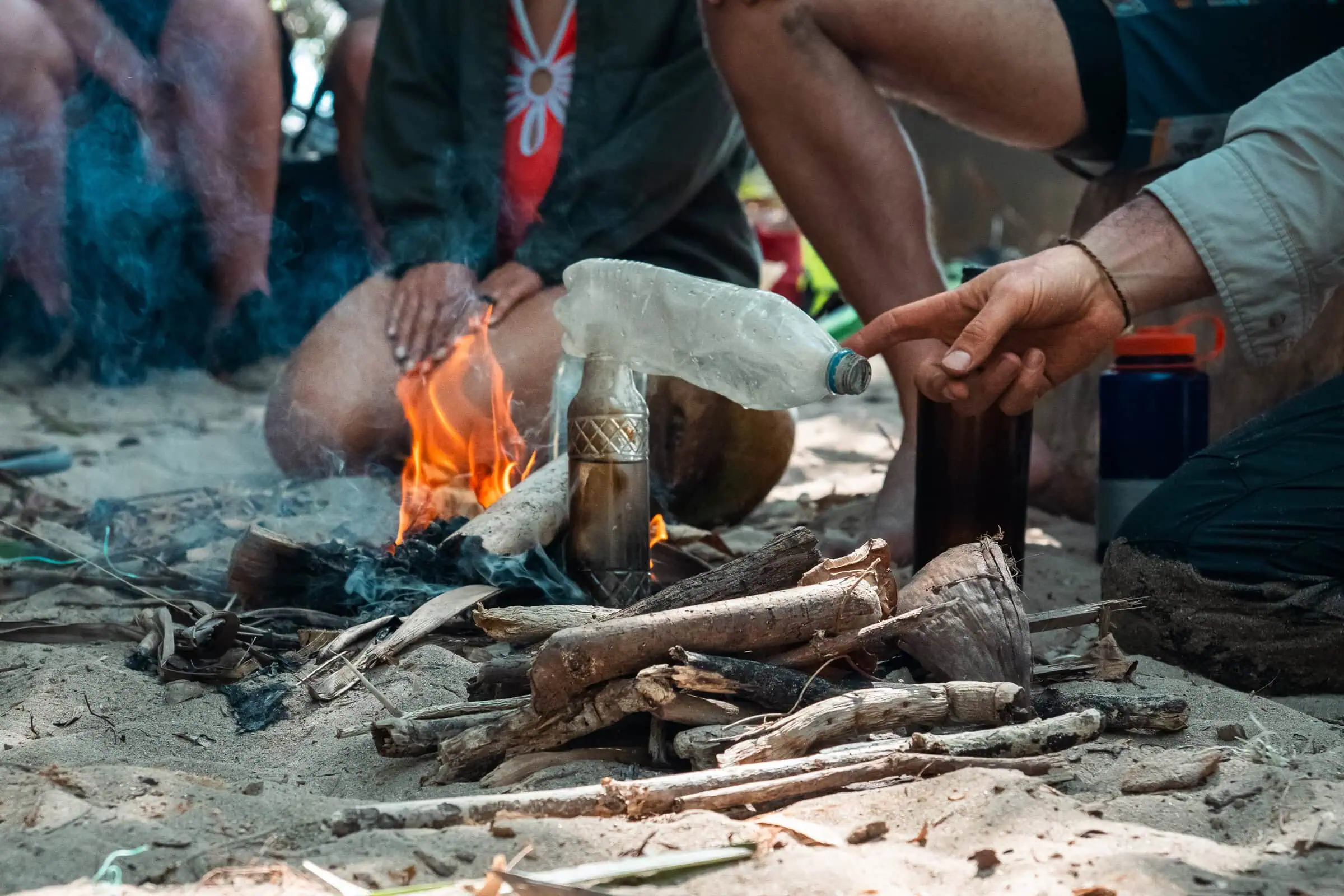 Survivalists purify water on a desert island, using natural materials for emergency heat and cooking.