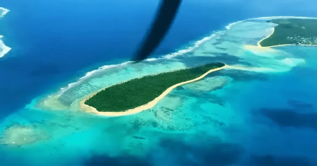 Desert Island Survival Adventure in Tonga 1 Aerial view of a tropical deserted island with lush greenery, white sandy beaches, and vibrant blue waters, perfect for survival adventure and island exploration.