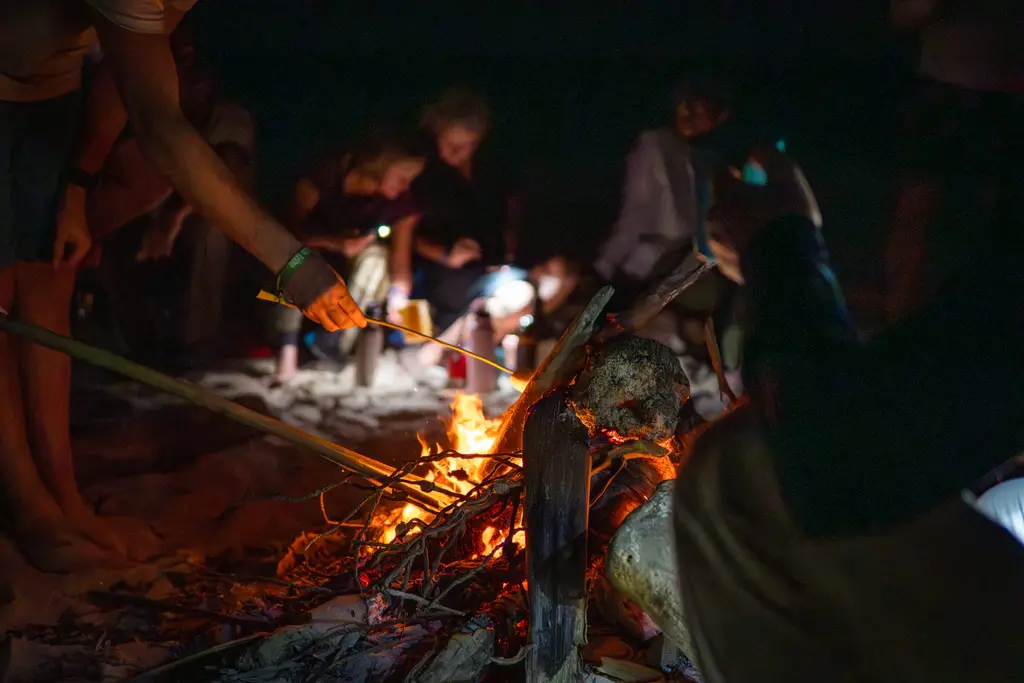 Campfire at night in Panama, with people gathered around. Panama survival adventure.