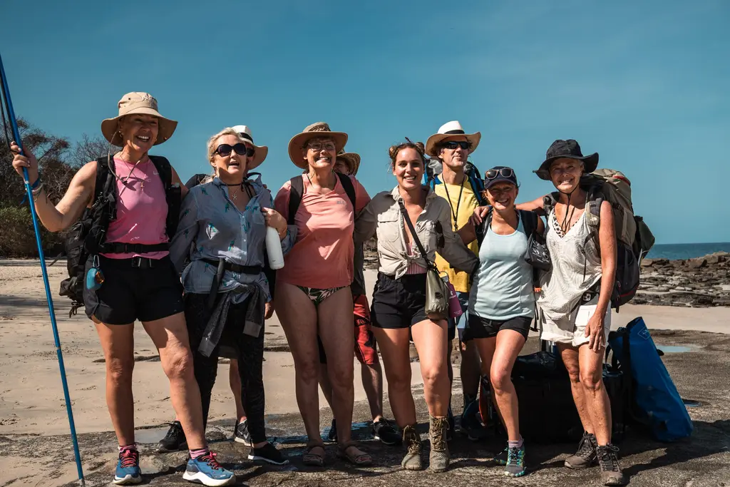 Group of hikers on a Panama adventure, smiling on a beach with backpacks and hats.