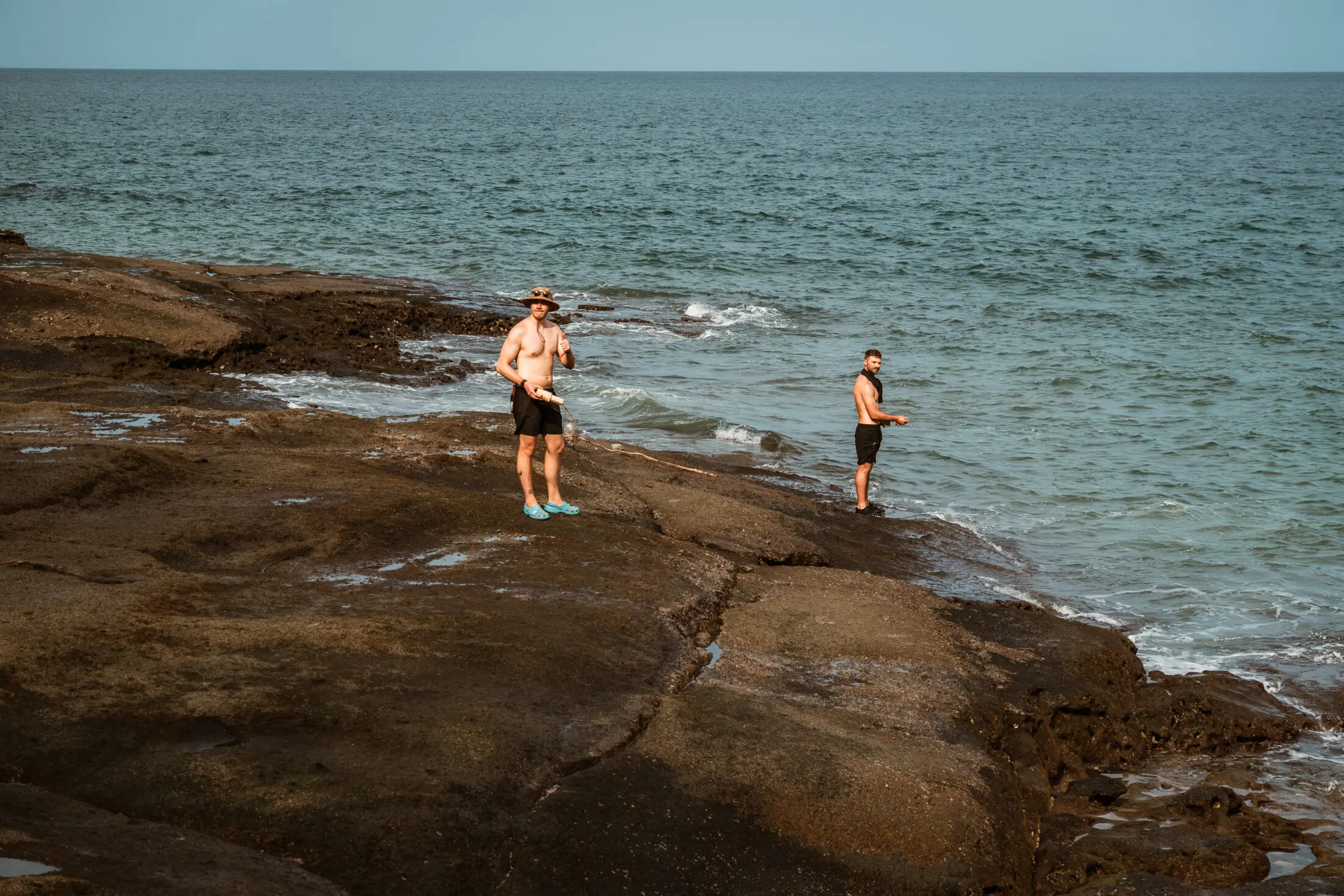 Why Real Adventure Demands Real Risk and Why We Manage It the Right Way 3 Two men fishing on a rocky coast, embodying the real risk in survival training.