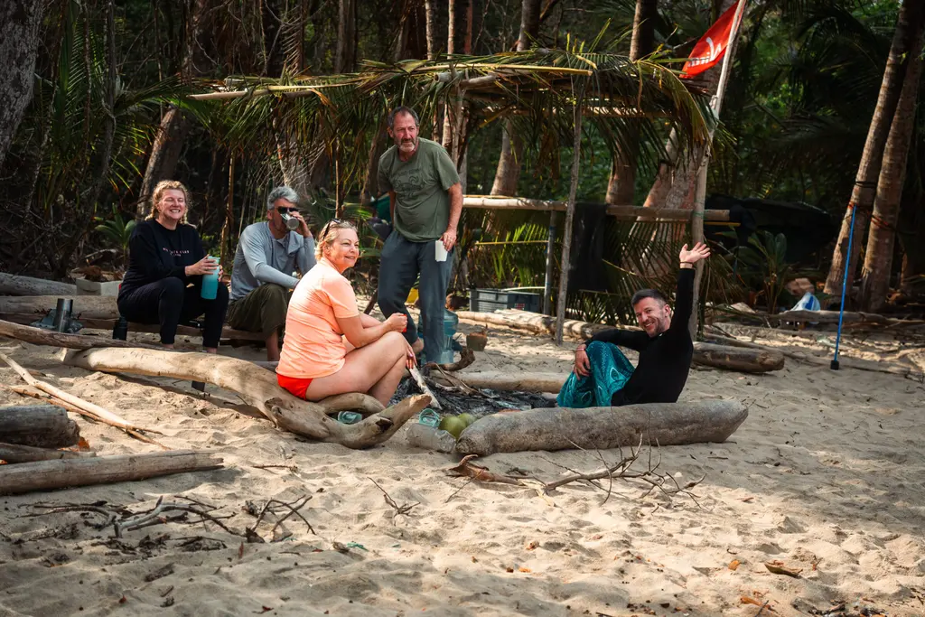 Group of people gathered around a fire on a Panama beach during a survival adventure.