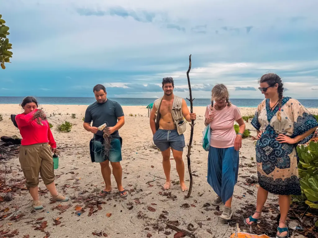 Group of people on a sandy beach, possibly after a cleanup, cloudy sky.