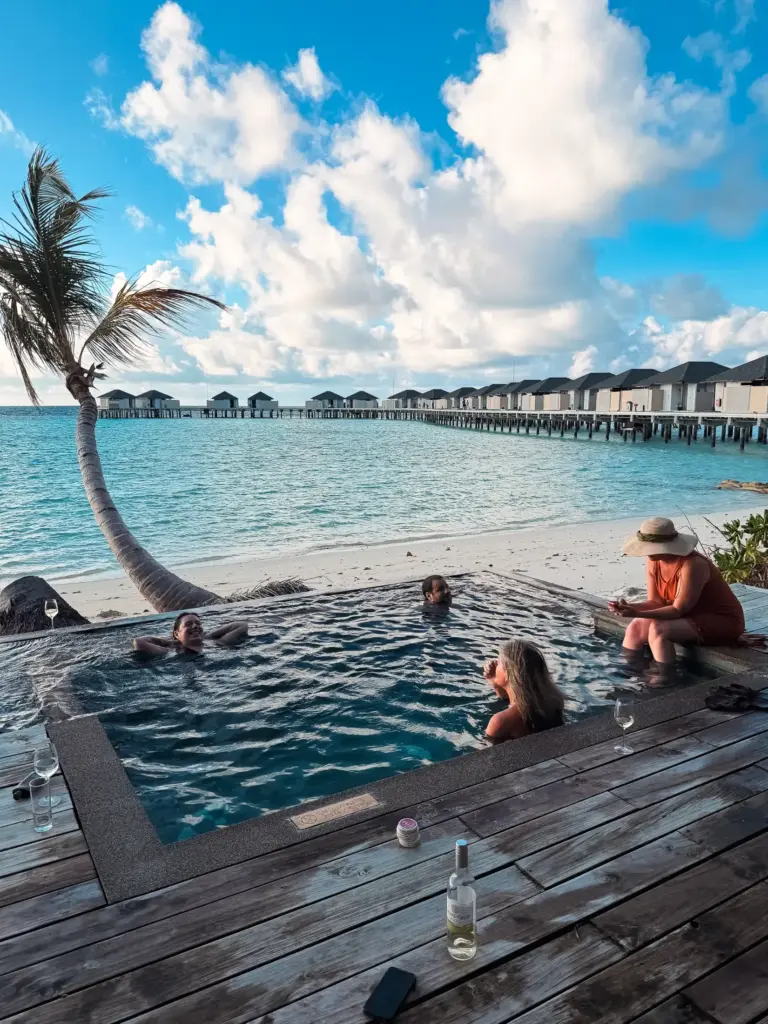 Maldives vacation: People relaxing in pool at overwater bungalow resort.