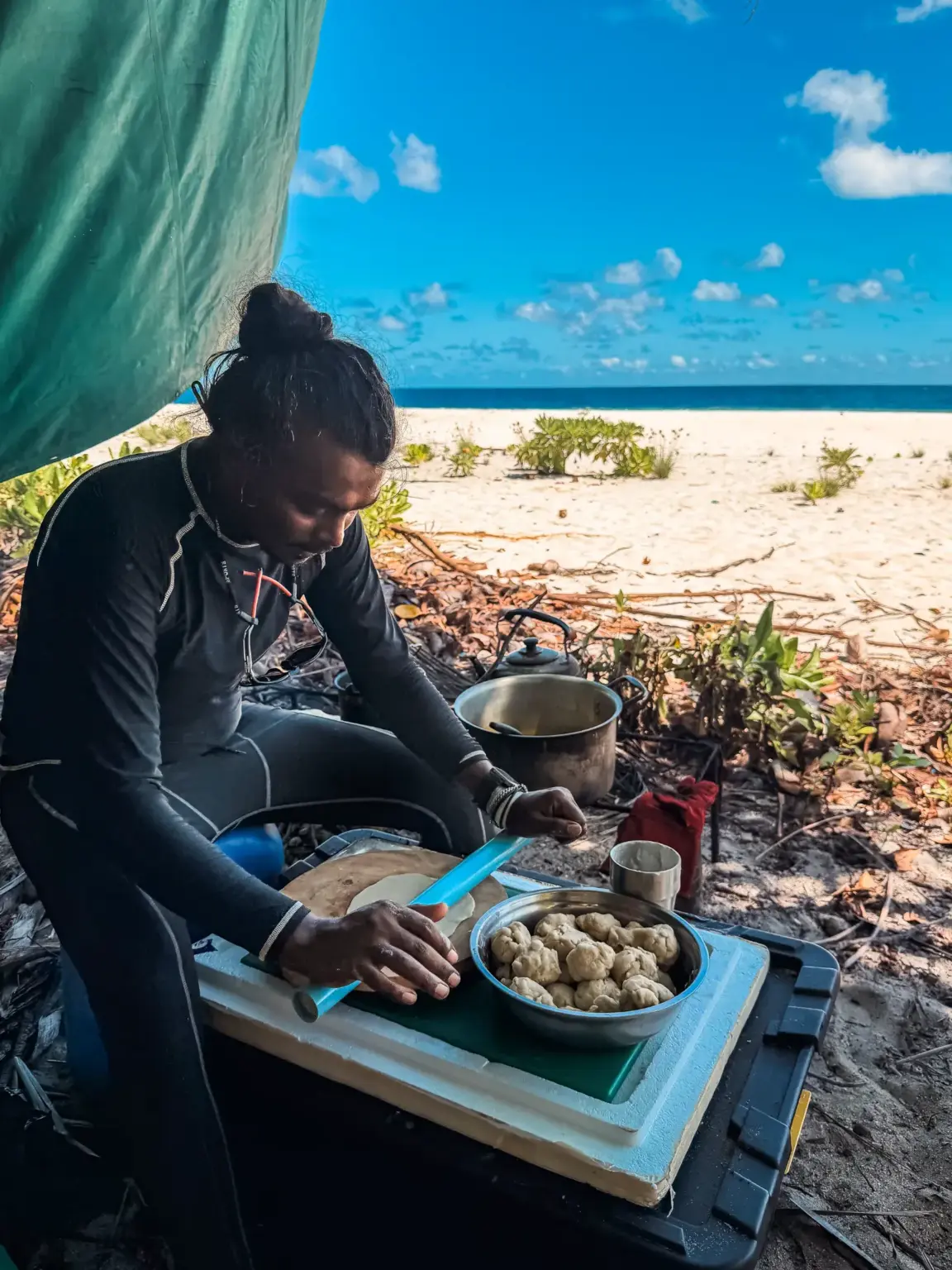 Man preparing food on a beach, Maldives. Survival skills in action.