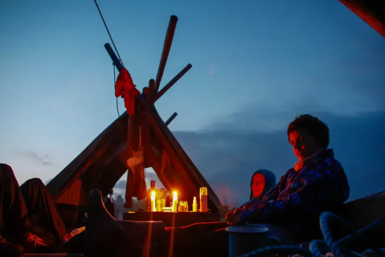 People on raft at dusk, Sweden expedition with candles and wooden structure.