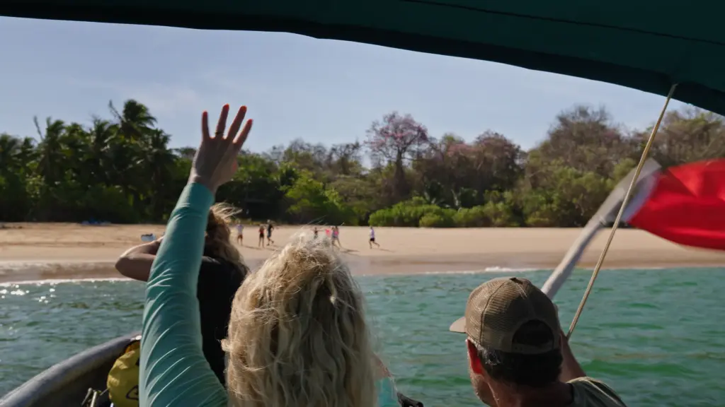 People on a tropical beach seen from a boat. Waving towards the shore.