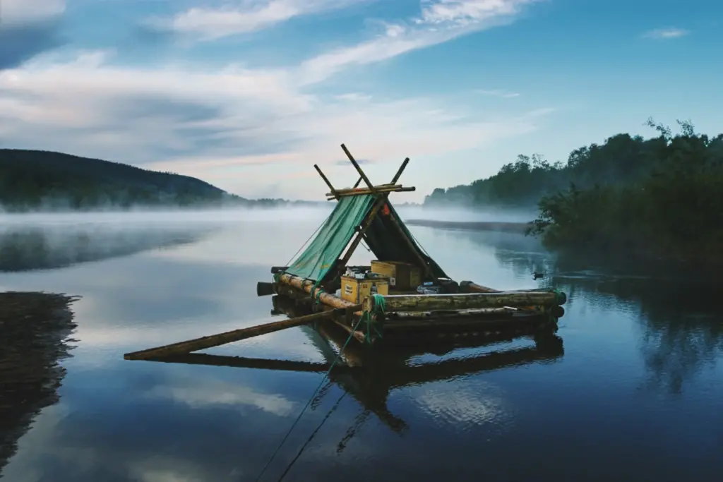 Handmade raft with tent on misty river, reflecting sky. Building a raft with mates for adventure.