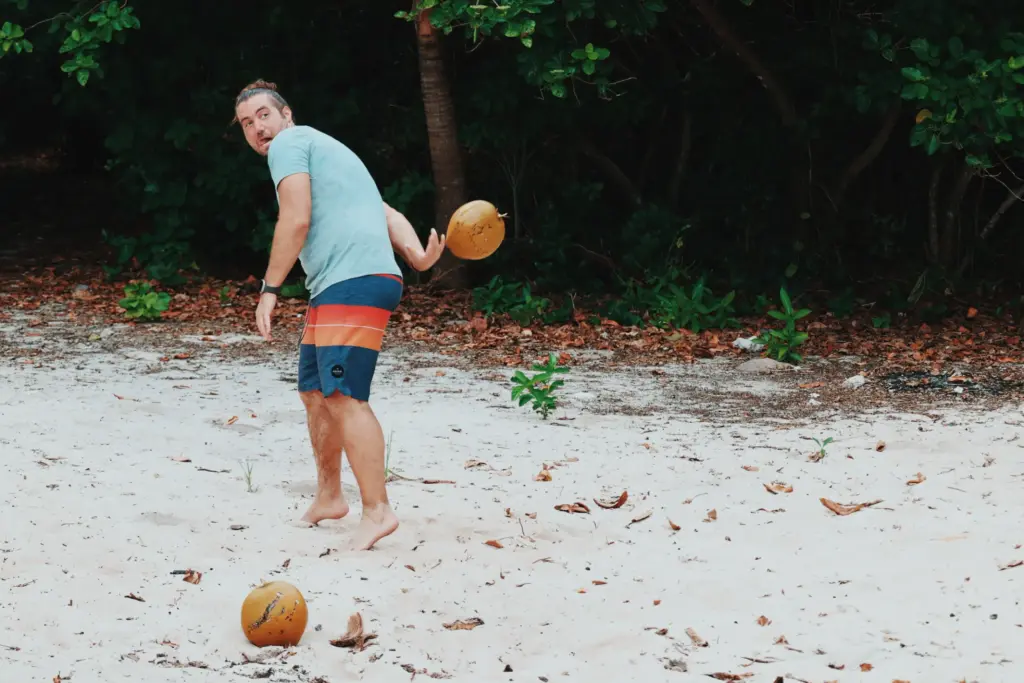 Man throwing coconut on beach, survival skills training.