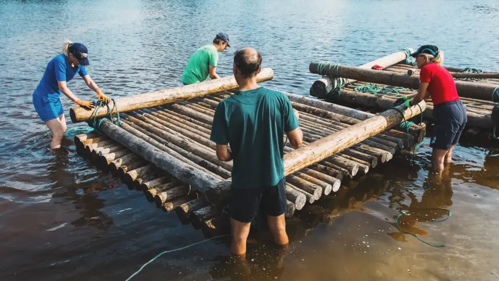 People building a raft together on a lake, teamwork and outdoor activity.