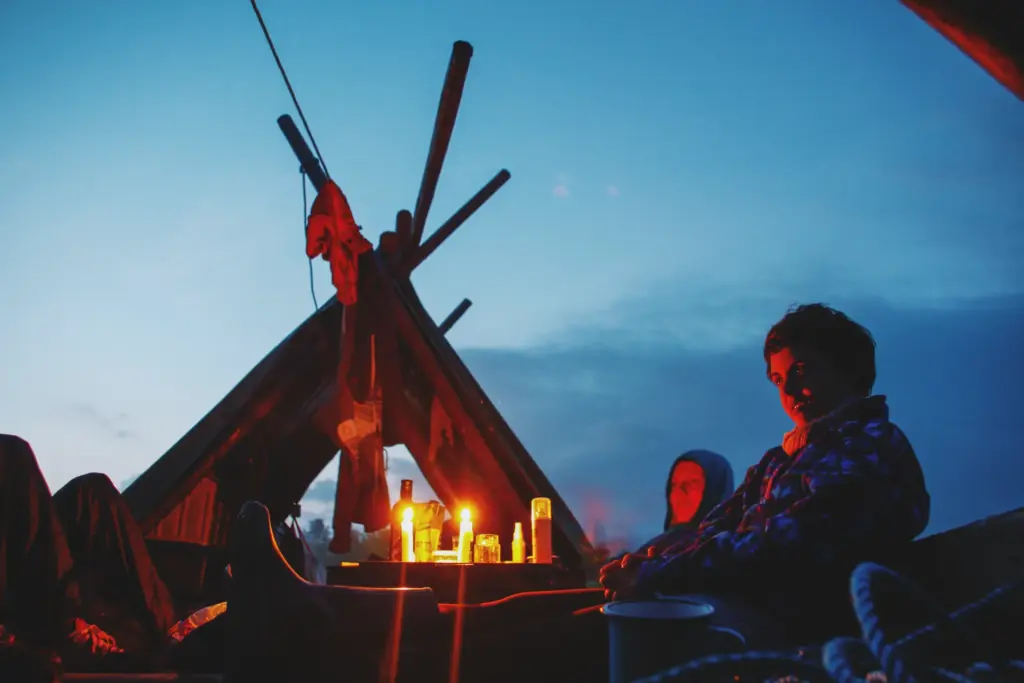 People gathered around a makeshift raft campfire at dusk.