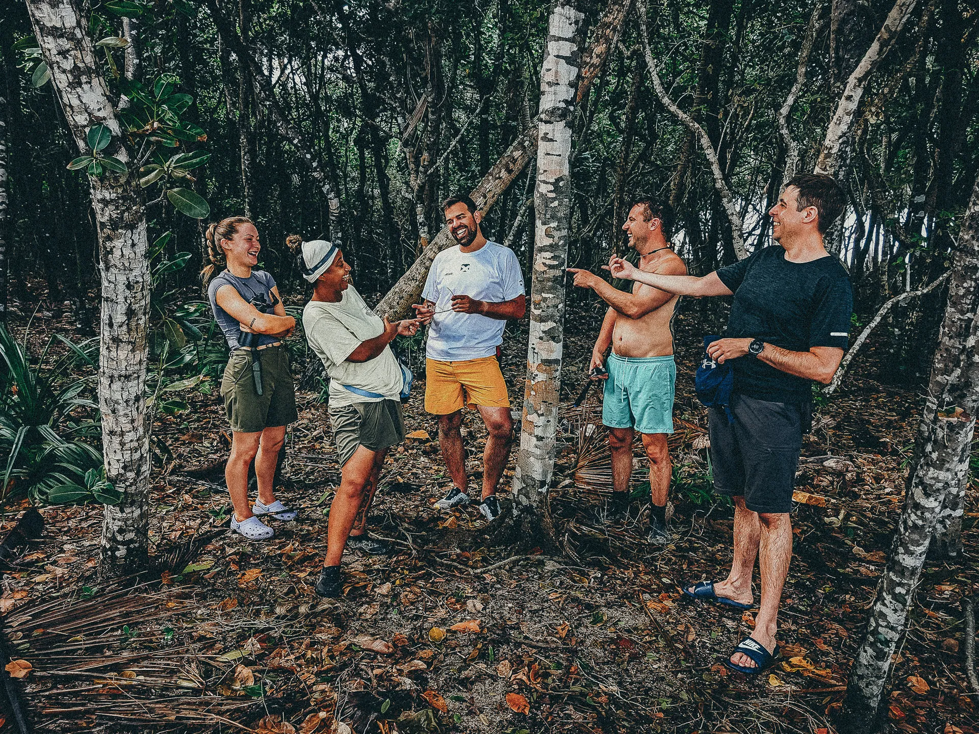 Group of people on expedition in forest, five smiling, one pointing