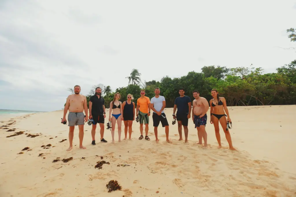 Group of people on a sandy beach, potentially after a survival expedition.